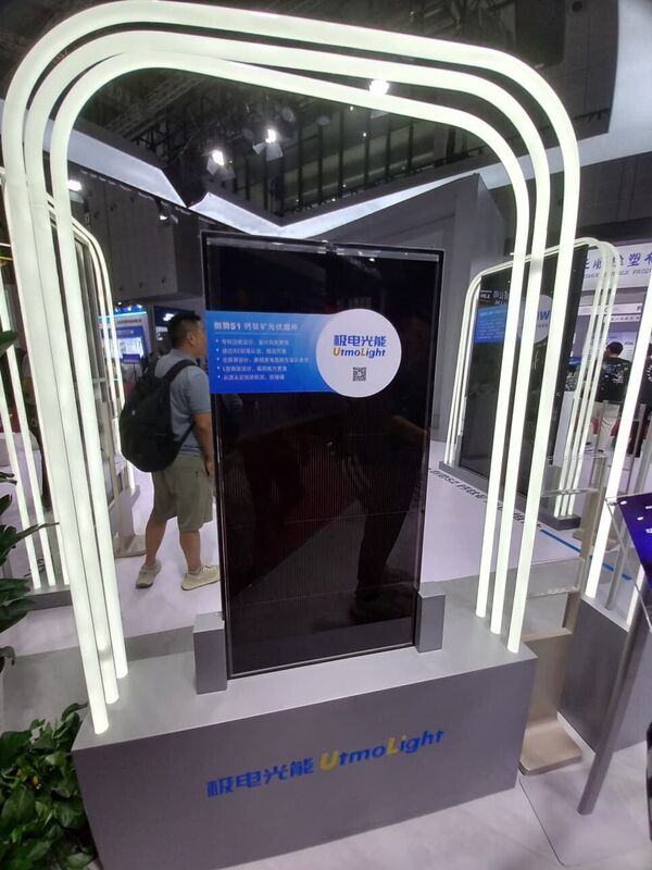 A tall vertical perovskite PV module displayed under curved white LED arches at the UtmoLight booth.