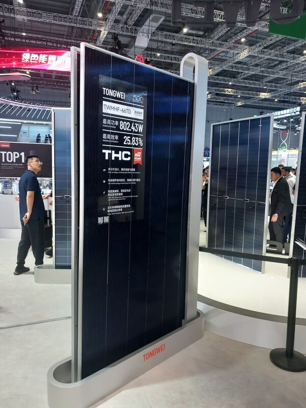 A large dark Tongwei solar module on a display stand with a specification label.