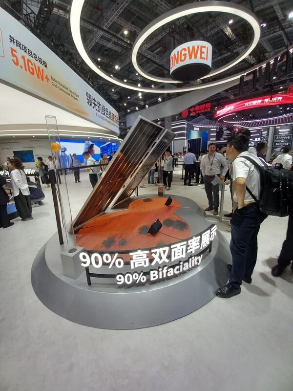 A tilted bifacial module demonstrator over a textured surface under a Tongwei sign.