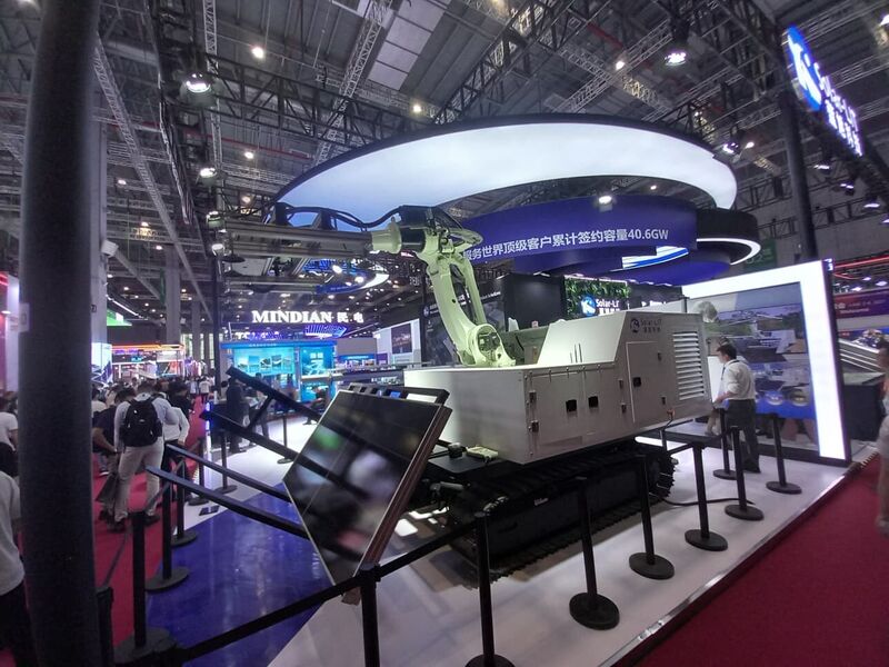 A tracked robotic platform with an articulated arm on an exhibition stand.