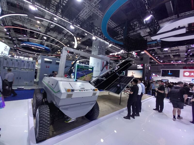 A rugged off-road autonomous vehicle with a robotic arm holding a solar module.